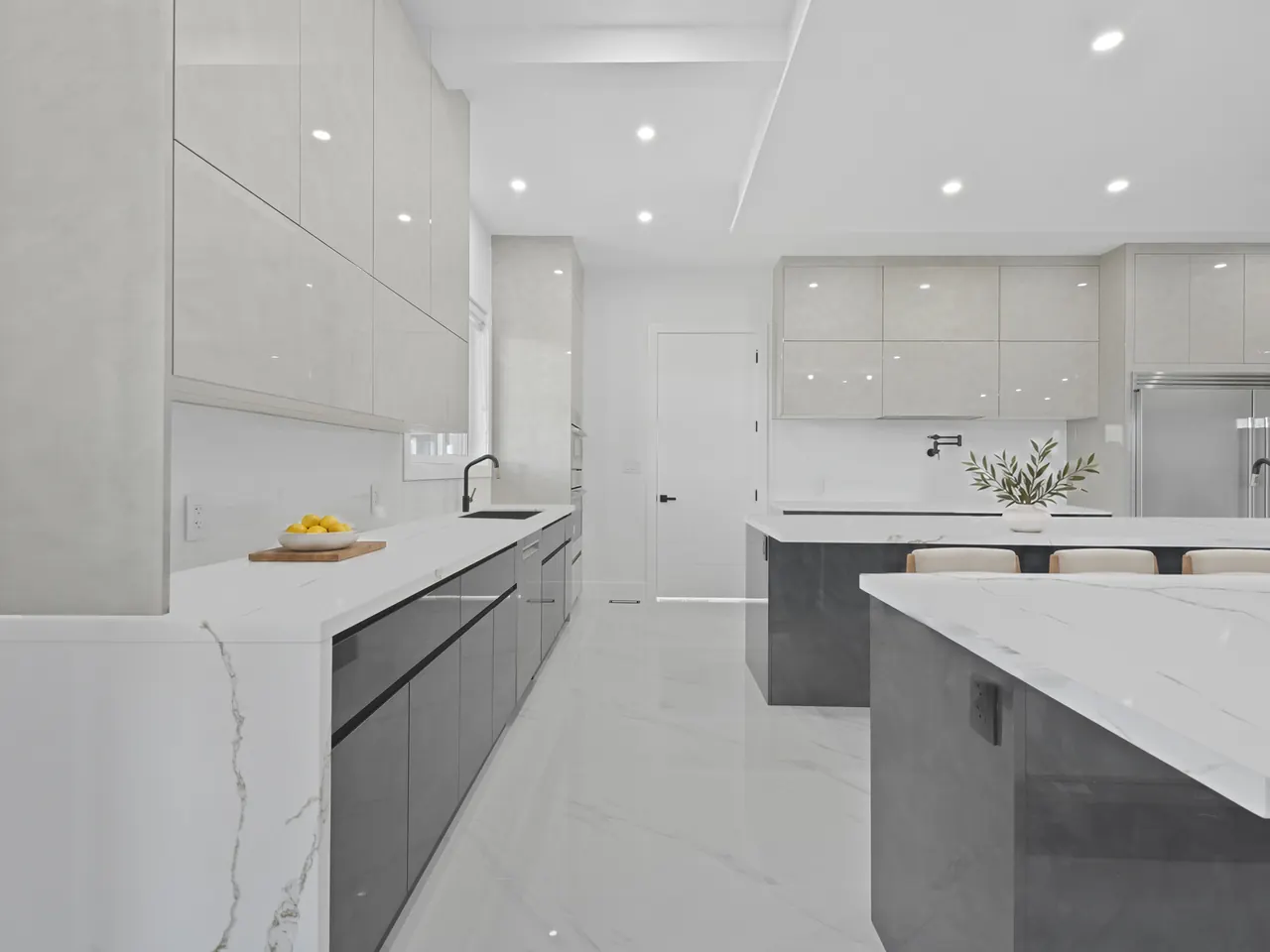 Kitchen with quartz waterfall islands and high-gloss cabinets, virtually staged with counter stools on the far side of the island